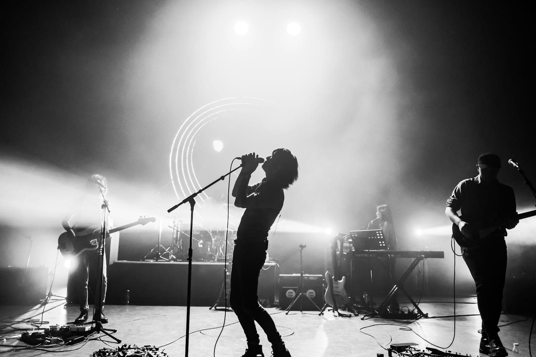 A singer and guitarist performing on a smoky stage, in black and white